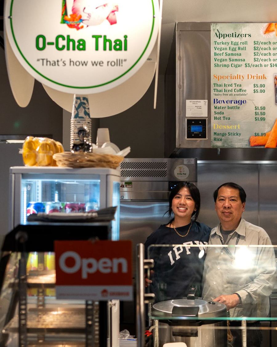 Tyla and her dad behind the counter at Union Street Market, under the O-Cha Thai sign